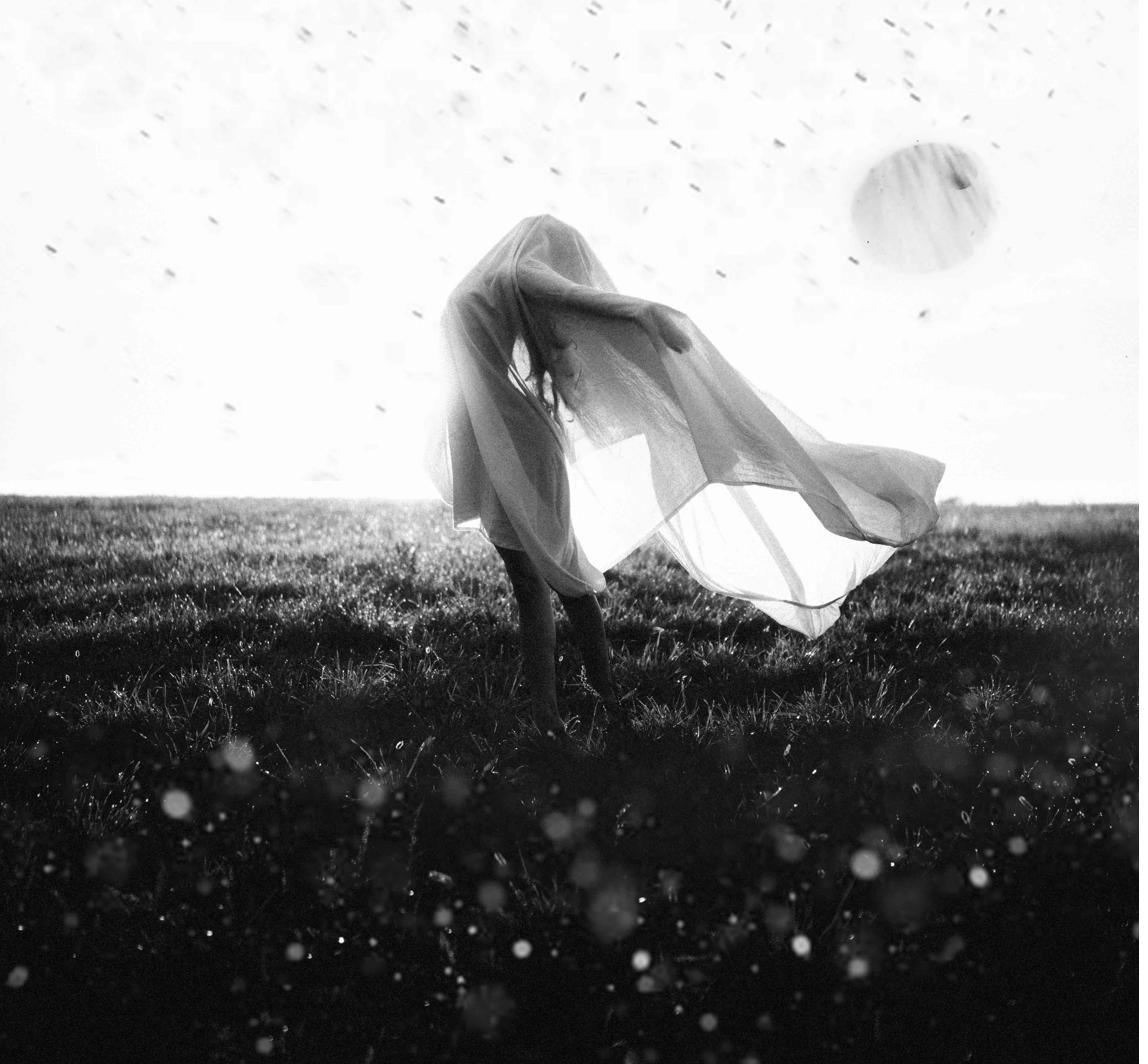 Portrait de mode en noir et blanc : femme au voile blanc dans un champ, photographié par Kevin Klaircq