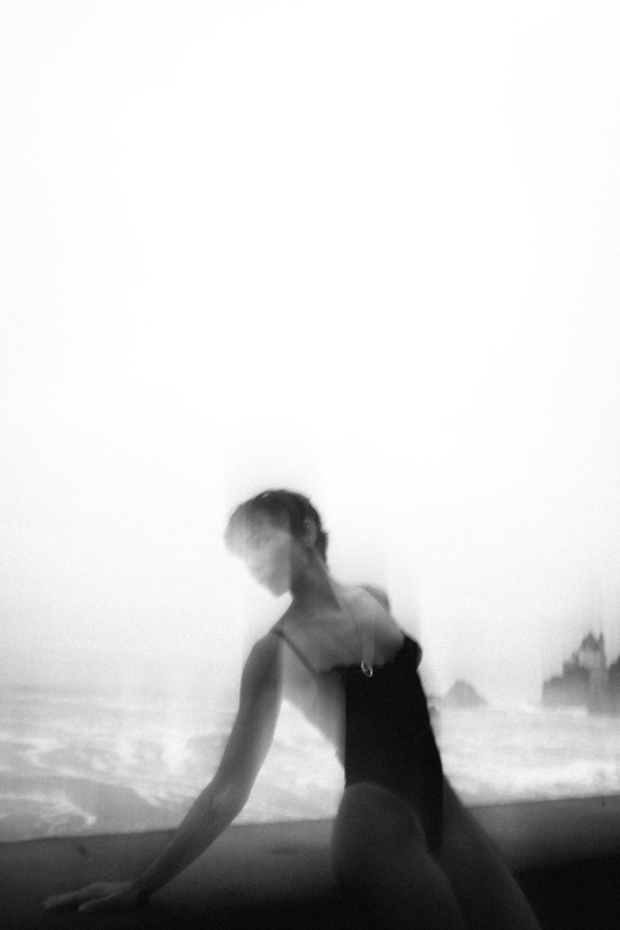 Portrait de mode dans la brume au bord de l'océan, tons clairs et flou artistique